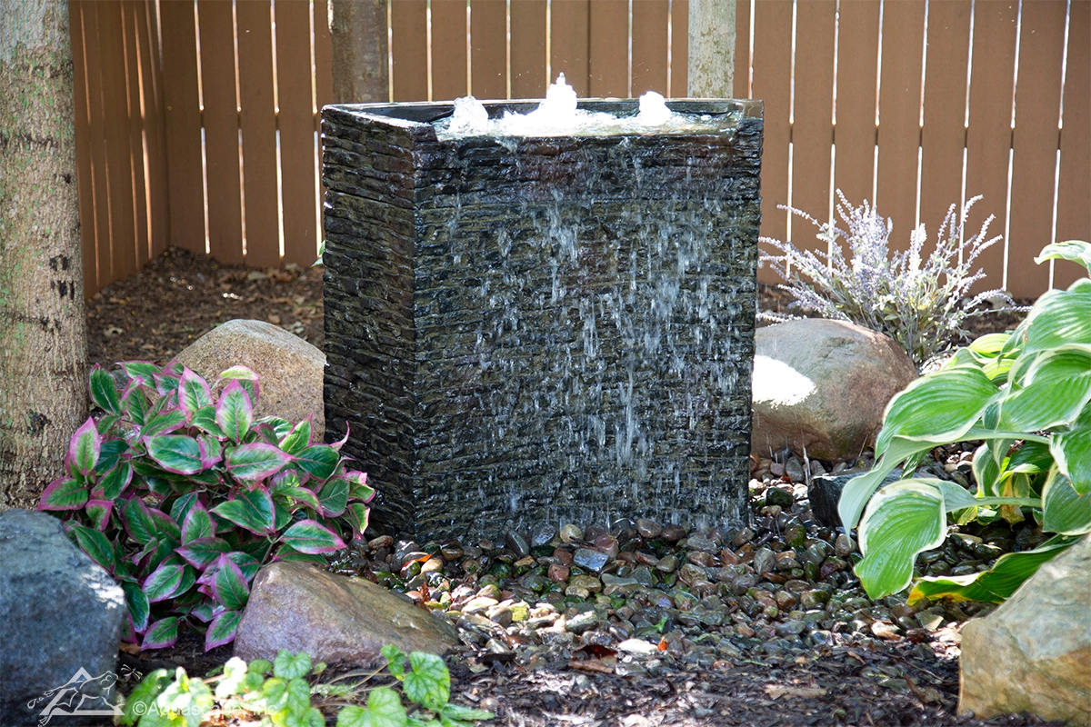 Stacked slate wall fountain in a landscaped setting