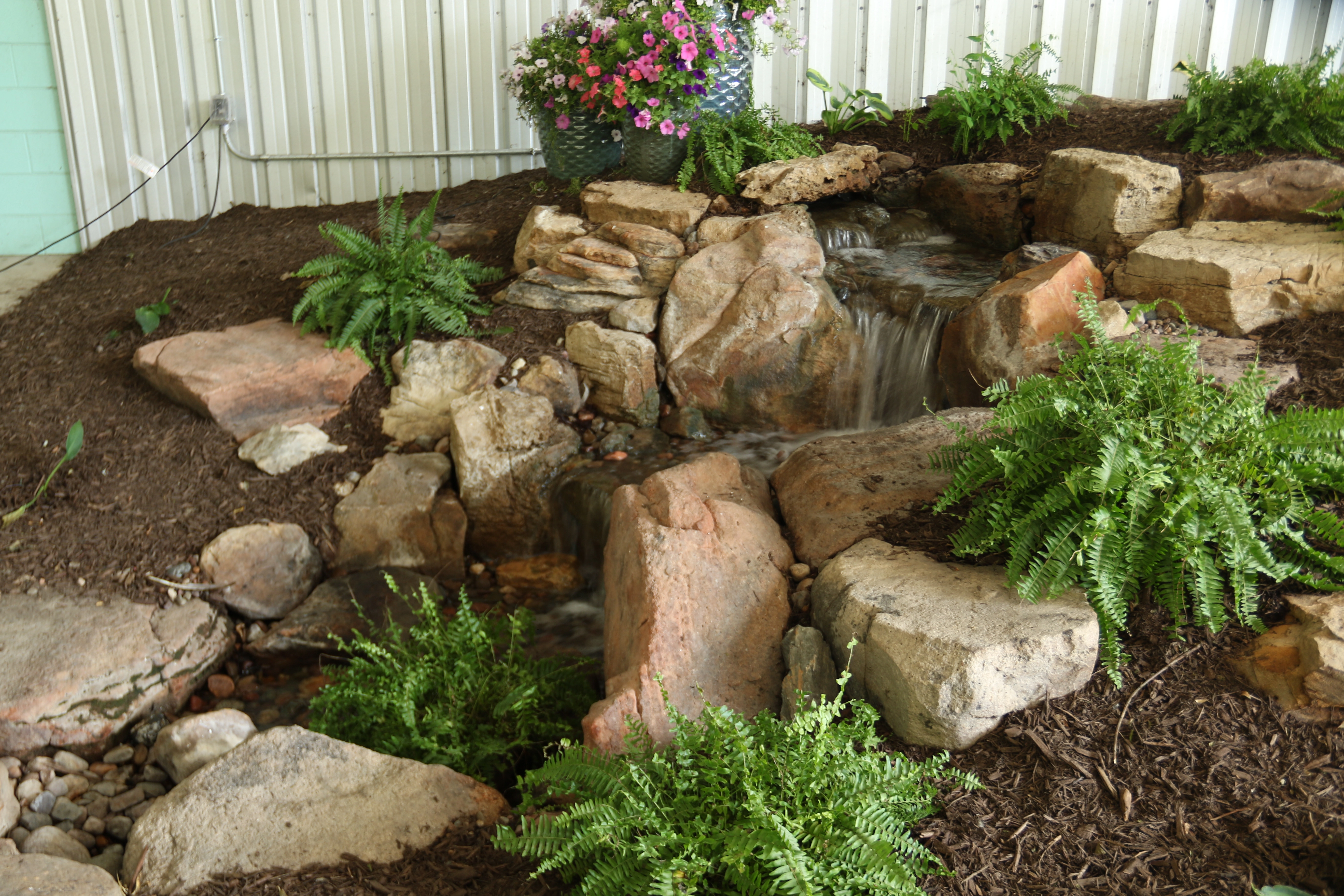 Tall natural-stone pondless waterfall fitted into a narrow space
