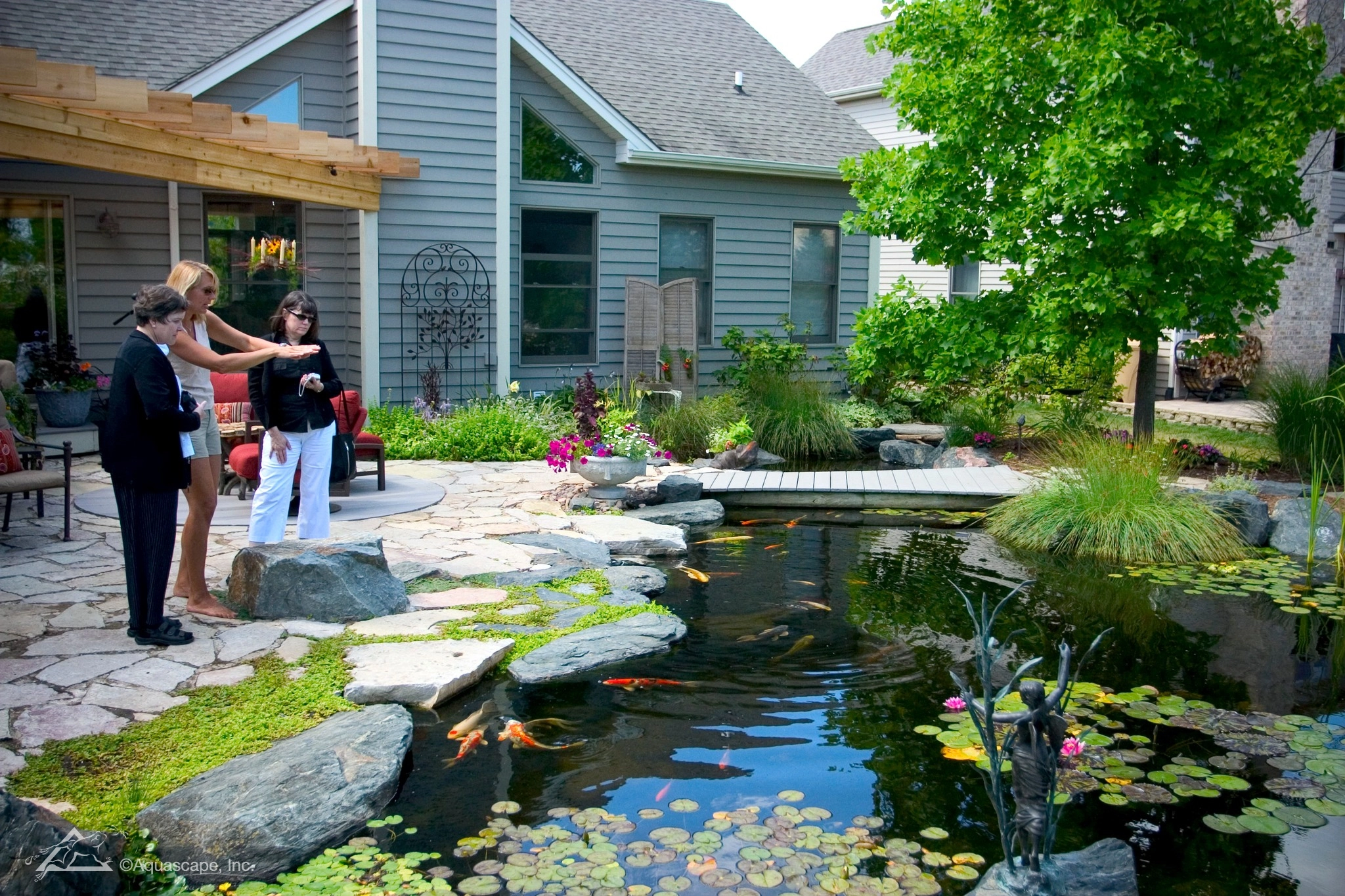 People standing beside a backyard ecosystem pond in Burnsville Minnesota