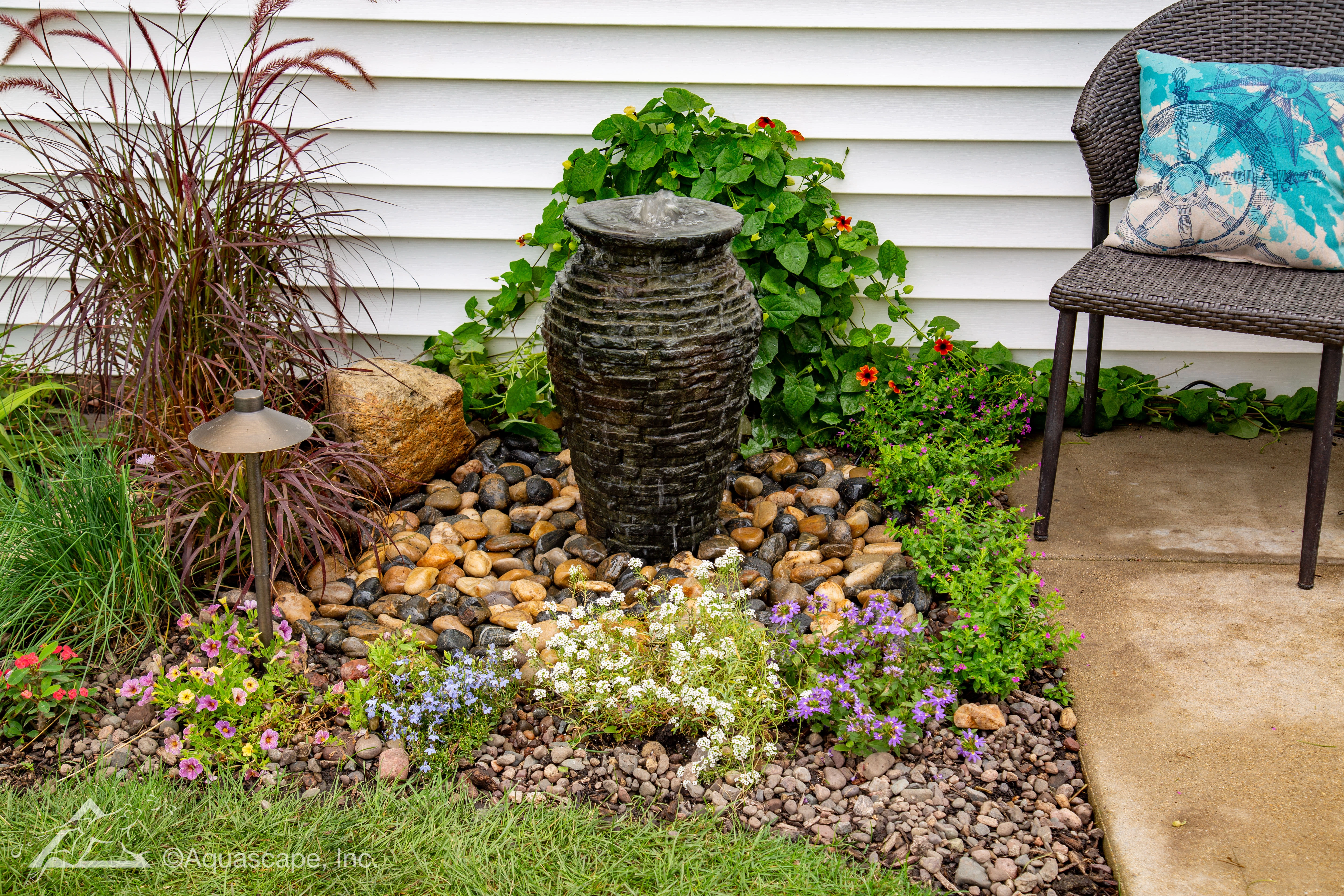 Small backyard fountainscape installed beside a patio seating area