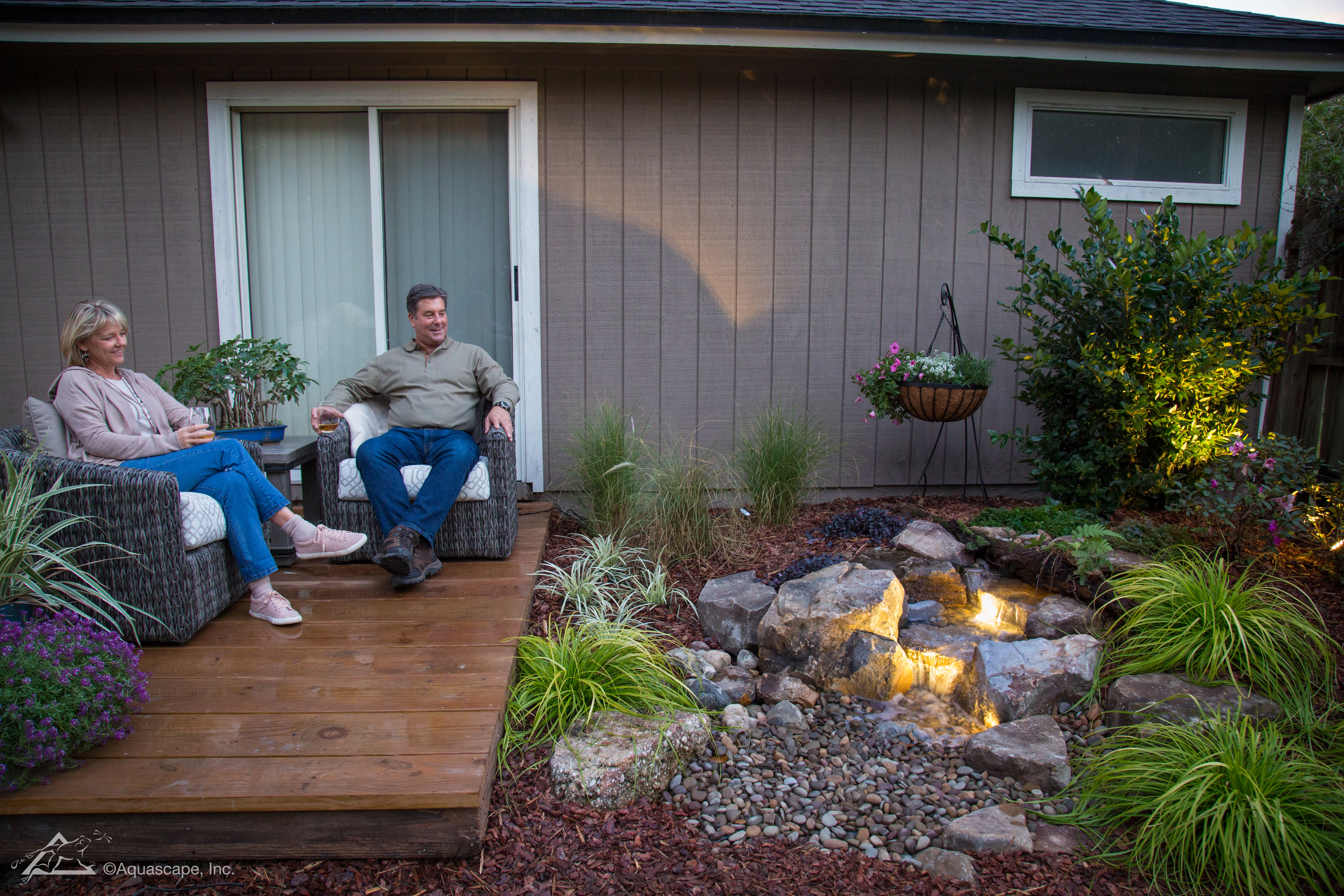 Family enjoying a pondless waterfall in an evening backyard setting near Chanhassen Minnesota