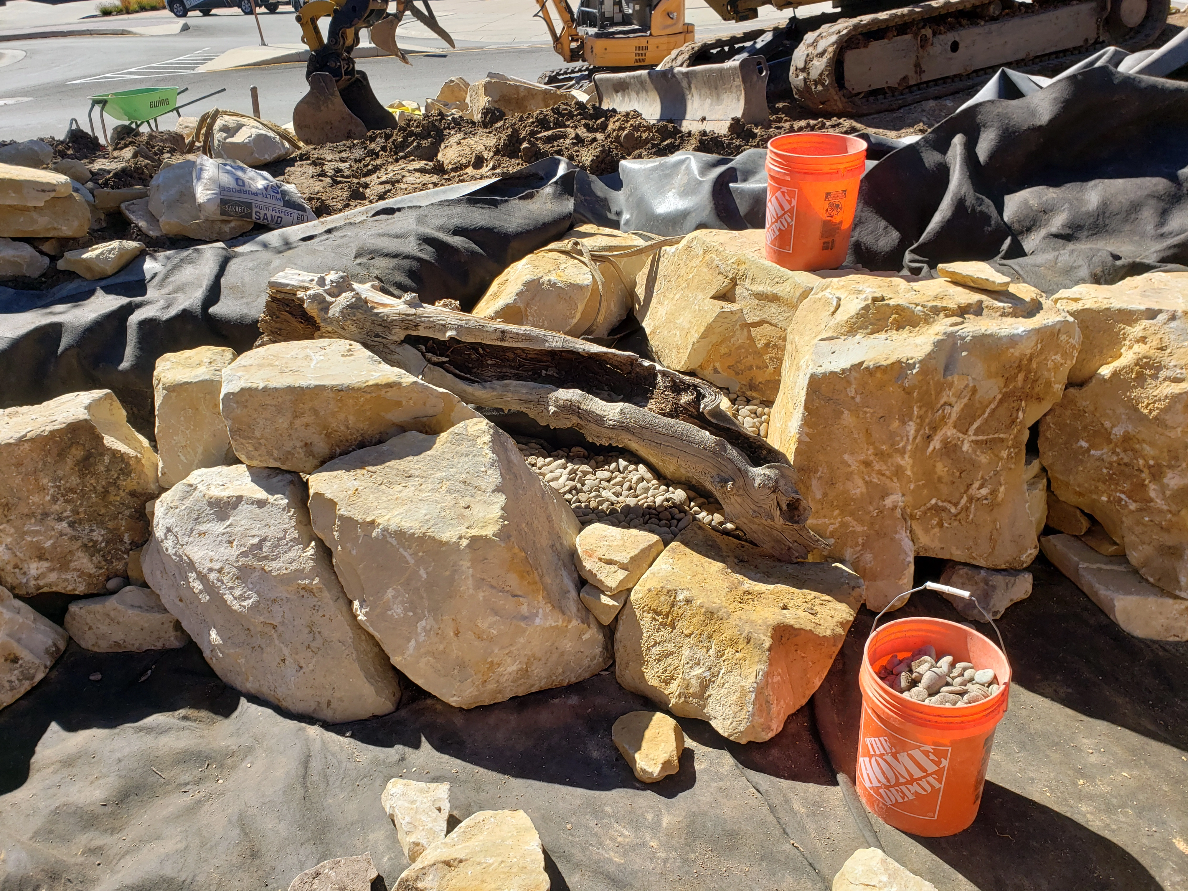 Premium pond and waterfall detail with natural driftwood, boulders, and gravel