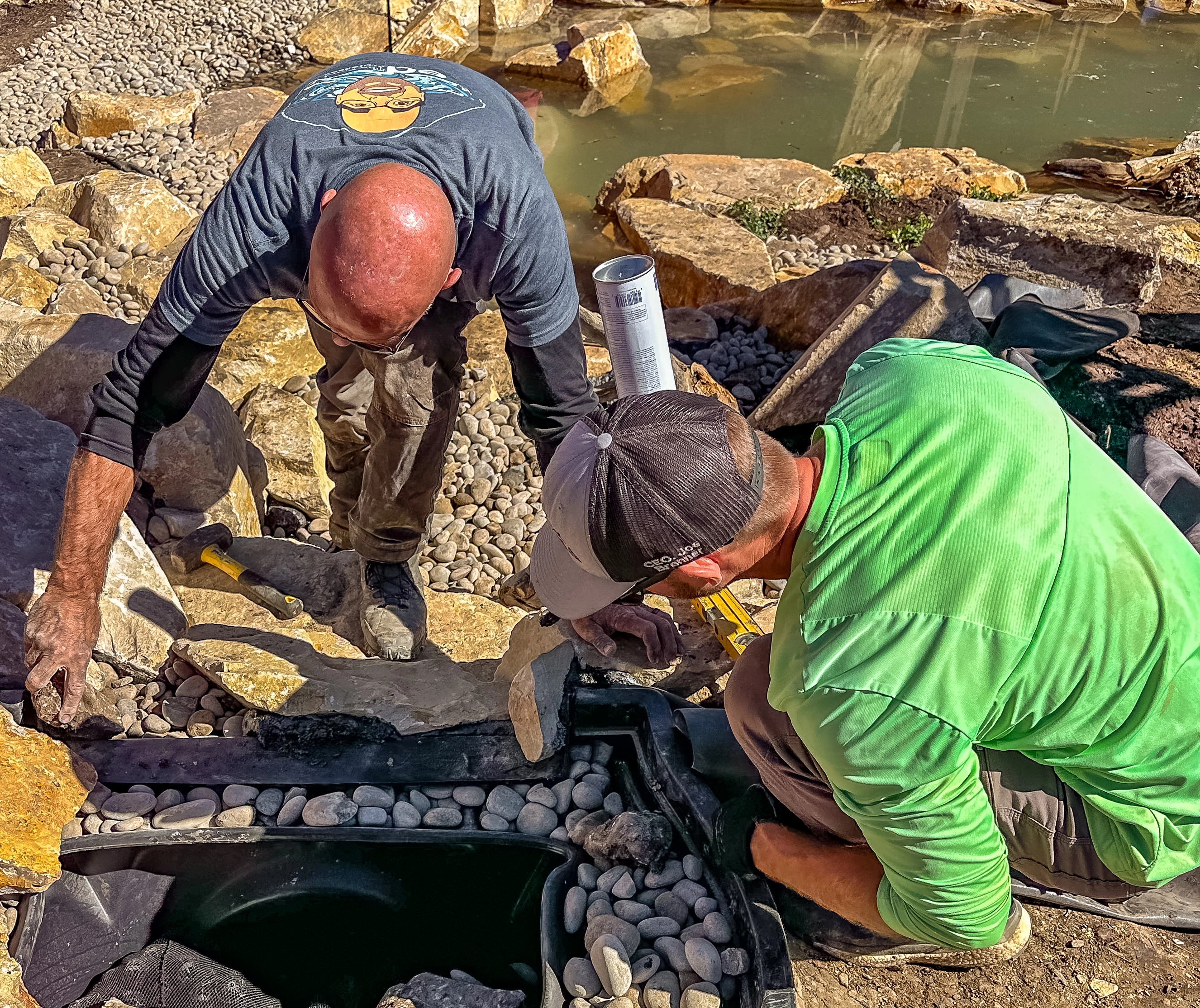 Professional waterfall spillway rock installation during pond construction