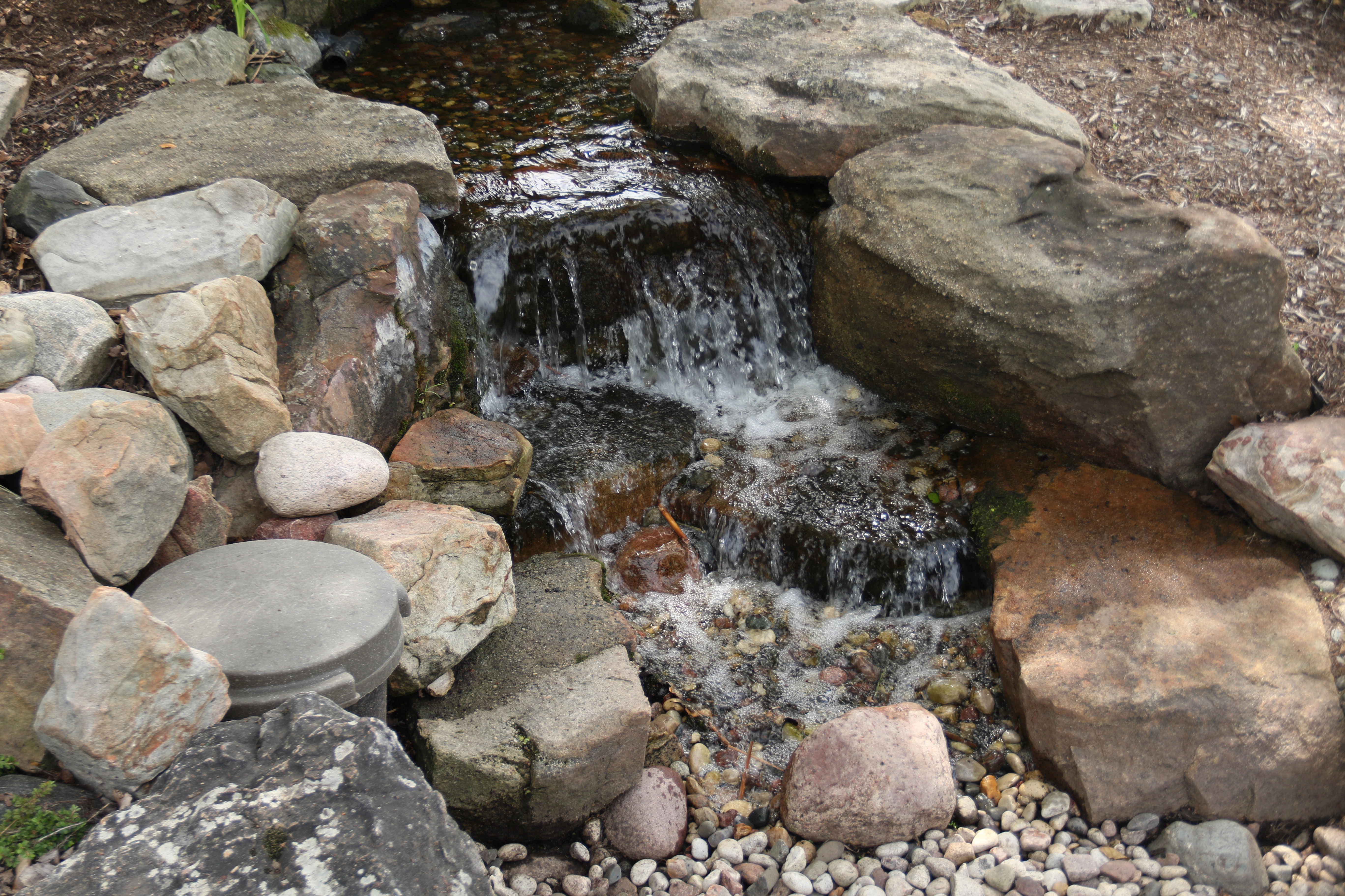 Pondless waterfall with moving water and natural stone in a Minnesota landscape
