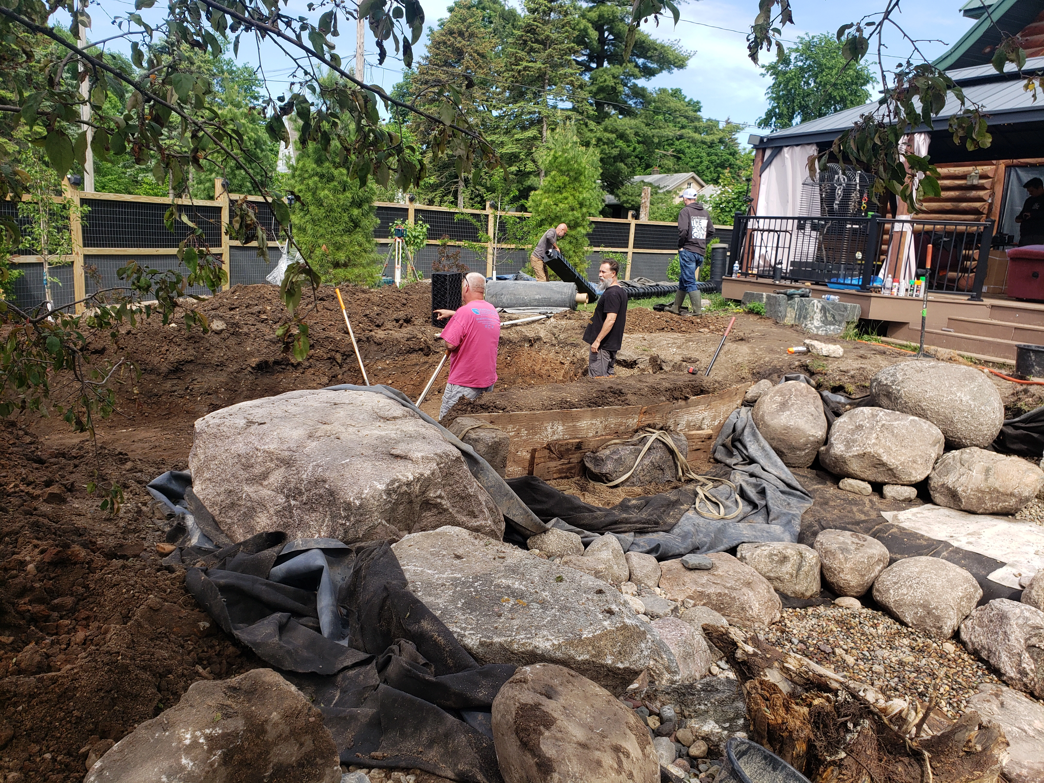 Pond excavation and rockwork during backyard water feature construction