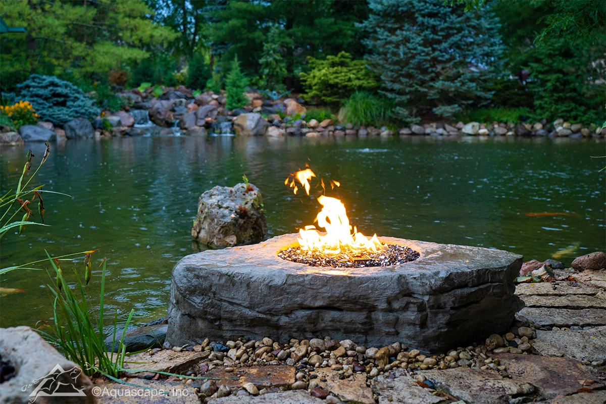 Fire feature near an ecosystem pond with natural stone and evening atmosphere