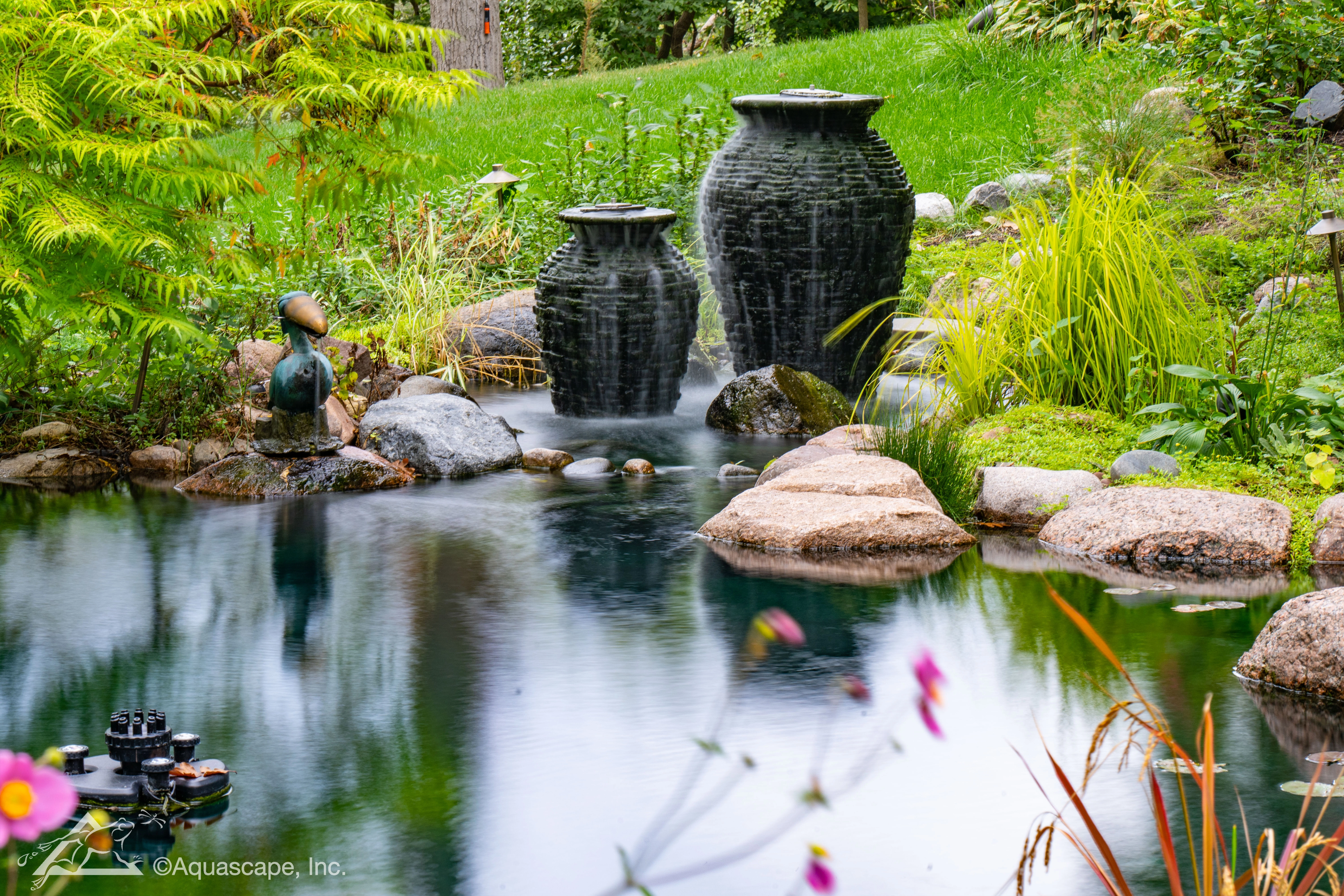 Backyard ecosystem pond with stacked slate urn fountains